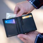 black leather bifold wallet on persons hand