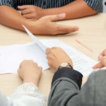 A lawyer and clients signing documents for a property sale in Greece, illustrating the process of calculating capital gains tax.
